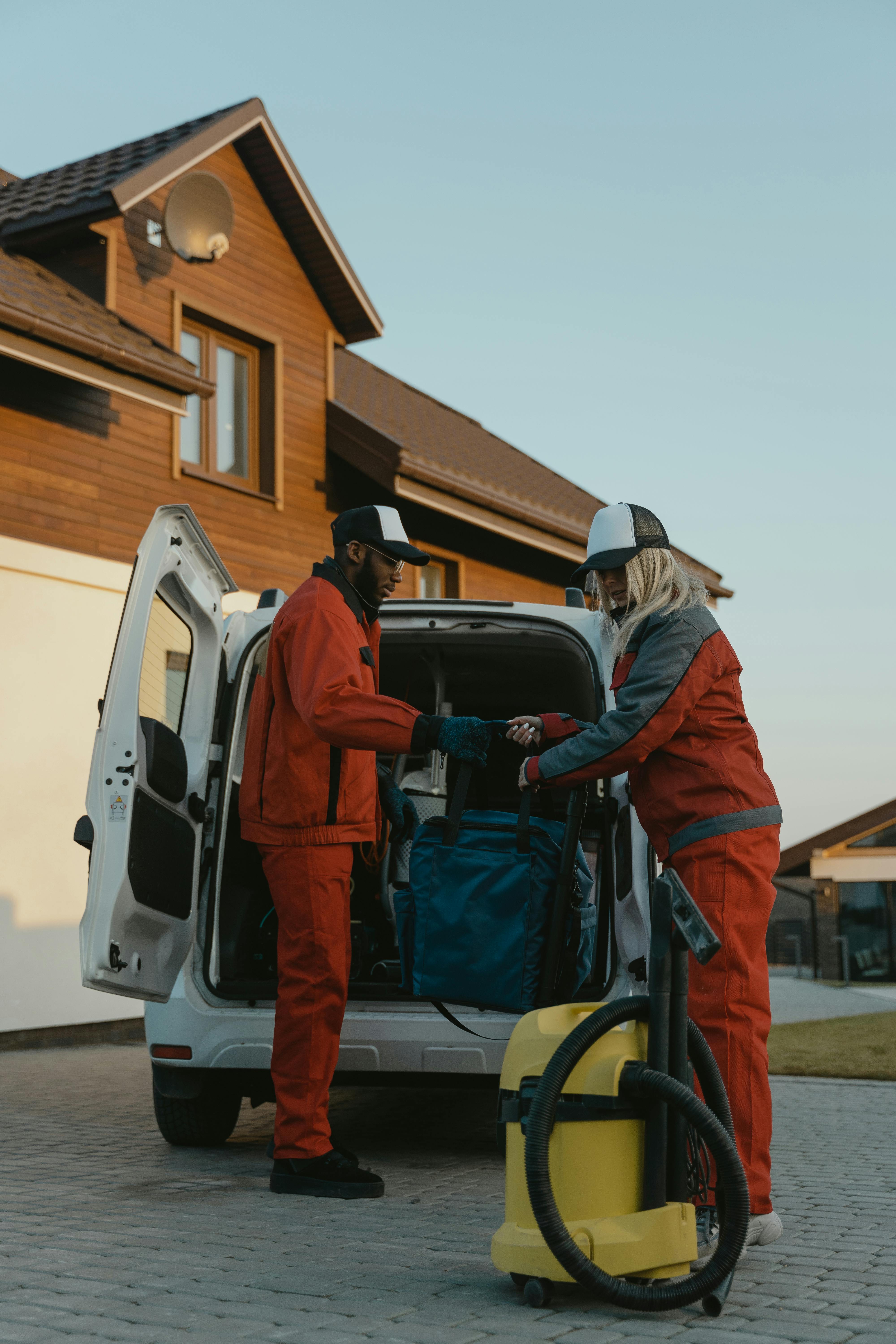 pexels-photo-6195879-6195879 Man in Orange Jacket and Gray Backpack Standing Beside White Van